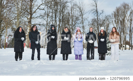 Group of schoolgirls holding snowballs, enjoying a winter day in a snowy park, ready for a snowball fight Group of schoolgirls holding snowballs, enjoying a winter day in a snowy park, ready for a snowball fight 120796995