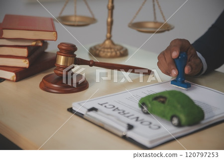 Judge gavel and miniature car symbolize auction or court case against driver who has accident and receiving vehicle insurance payment be on table in front of hands of lawyers. Selective focus Judge gavel and miniature car symbolize auction or court case against driver who has accident and receiving vehicle insurance payment be on table in front of hands of lawyers. Selective focus 120797253