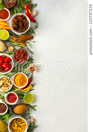 Various cooking spices and herbs spread across a neutral gray background, showcasing their rich, natural tones, top view and copy space 120797528