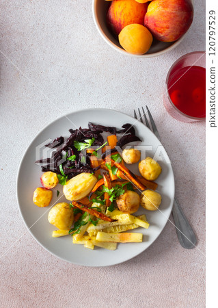 This nutritious meal includes oven-baked potatoes, zucchini, carrots, and beets, served with a refreshing cherry compote, making for a balanced and flavorful breakfast or lunch 120797529