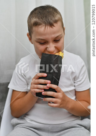 the boy eats delicious shawarma with an appetite. the boy eats delicious shawarma with an appetite. 120799015