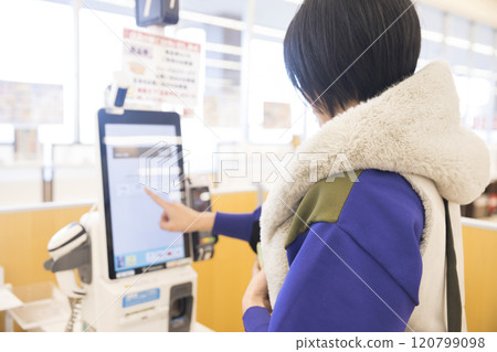 A young woman paying at a supermarket self-checkout 120799098