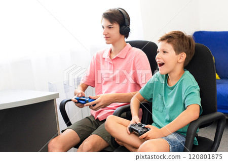 Teenager plays a computer game with headphones and a joystick, game console. Teenager plays a computer game with headphones and a joystick, game console. 120801875