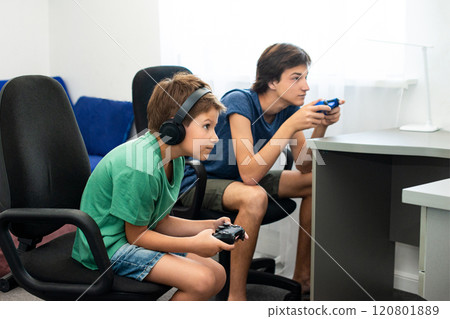 Teenager plays a computer game with headphones and a joystick, game console. 120801889