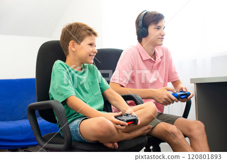 Teenager plays a computer game with headphones and a joystick, game console. Teenager plays a computer game with headphones and a joystick, game console. 120801893