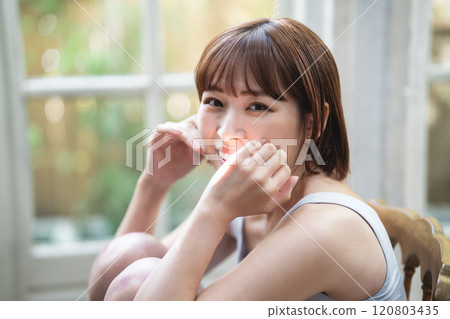 A young woman with a short bob relaxing by the window 120803435