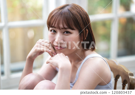 A young woman with a short bob relaxing by the window A young woman with a short bob relaxing by the window 120803437