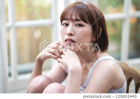 A young woman with a short bob relaxing by the window 120803440