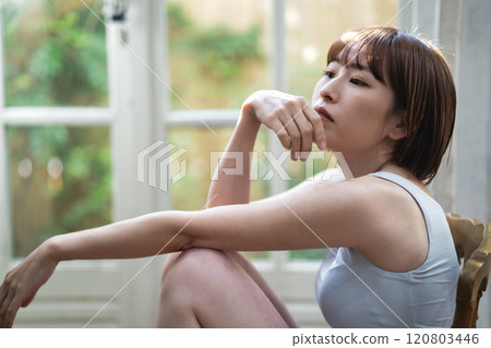 A young woman with a short bob relaxing by the window A young woman with a short bob relaxing by the window 120803446