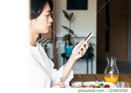 女人看著智能手機時吃早餐 120805080