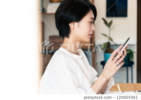 Woman eating breakfast while looking at smartphone 120805081