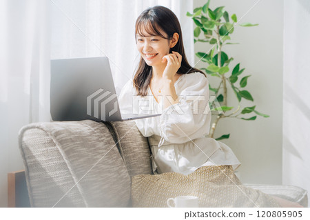 Woman using a computer on the sofa 120805905