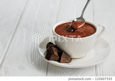 hot chocolate in cup and in spoon on white wooden table 120807593