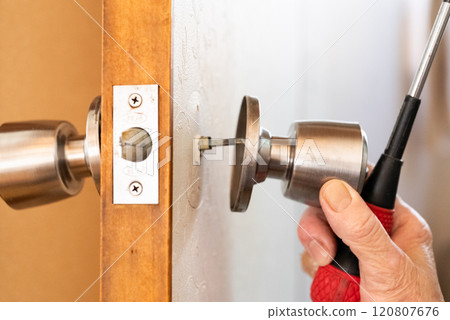 Senior woman's hands fixing the doorknob of an old house 120807676