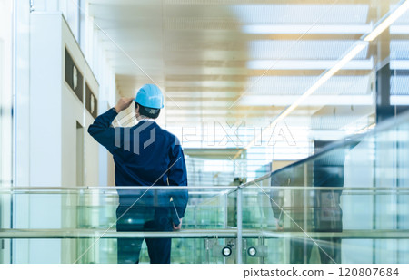 Back view of a male worker wearing a helmet inside a building 120807684