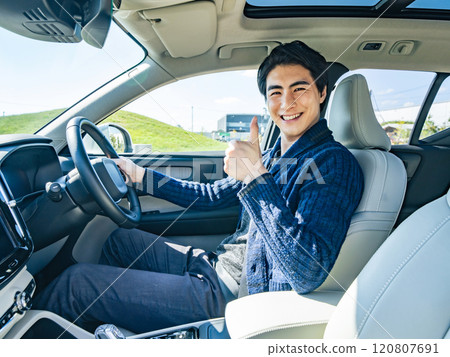 Male driver giving thumbs up in a car 120807691