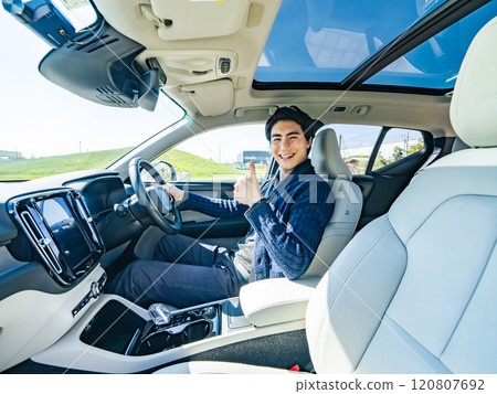 Male driver giving thumbs up in a car 120807692