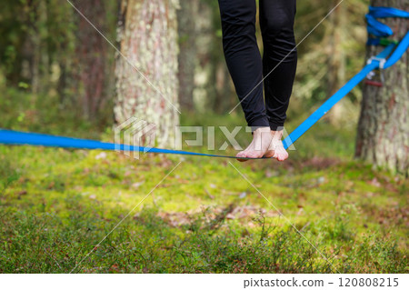 Close-up of feet balancing on a slackline in a lush forest setting Close-up of feet balancing on a slackline in a lush forest setting 120808215