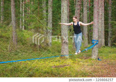 Teenage girl balancing on a slackline in the forest 120808257