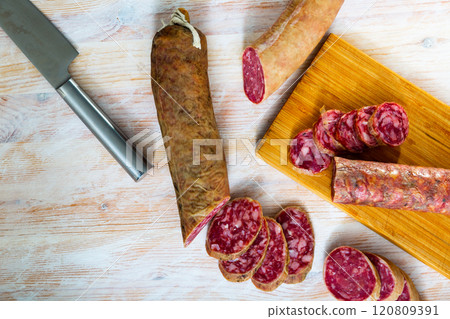 Spanish salchichon sausage cut in slices on a wooden surface 120809391
