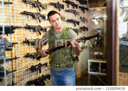 Man with rifle in weapon shop 120809439