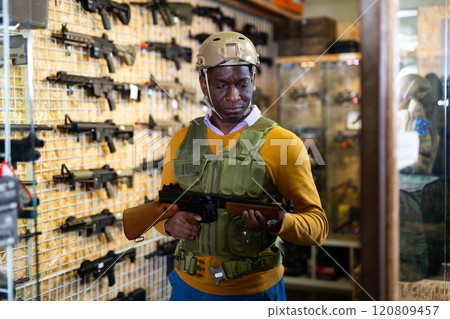 Man choosing machine gun in arms shop Man choosing machine gun in arms shop 120809457