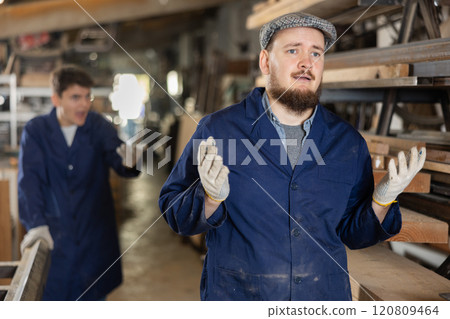 Young male carpenters quarreling in workshop 120809464