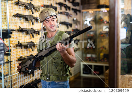 Man choosing rifle in airsoft shop 120809469