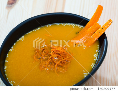 Tasty carrot cream soup with carrot served at plate on table 120809577