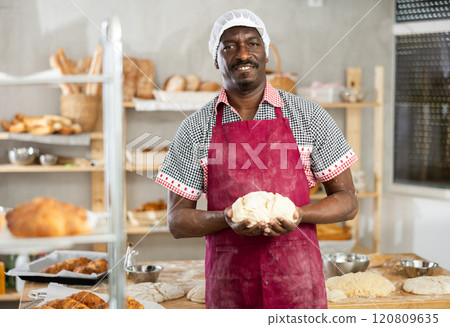 Smiling African baker standing with dough in cozy bakery Smiling African baker standing with dough in cozy bakery 120809635