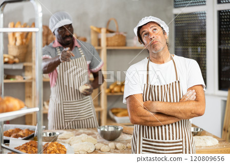 In bakery kitchen, confused Caucasian male employee during quarrel with man boss In bakery kitchen, confused Caucasian male employee during quarrel with man boss 120809656