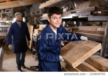Young guy takes wooden board from stack Young guy takes wooden board from stack 120809795