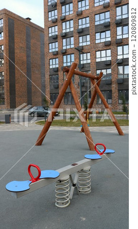 children's playground in the courtyard of a residential complex made of brown brick with swings made of natural materials, vertical shot, play area inside an apartment district in the city 120809812