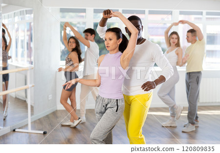 Men and women are standing next to each other and dancing in pair of salsa. Students practice repeating movements of pair dance 120809835