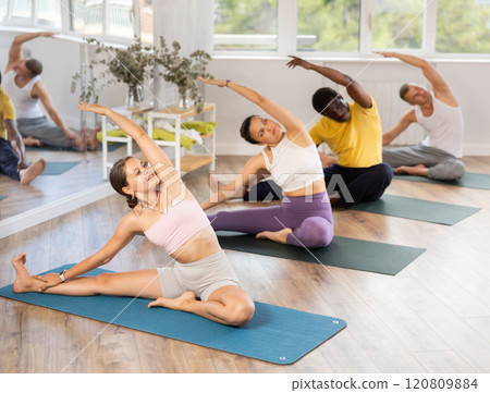 Young girl performing arivrtta Janu Sirsasana in yoga class Young girl performing arivrtta Janu Sirsasana in yoga class 120809884