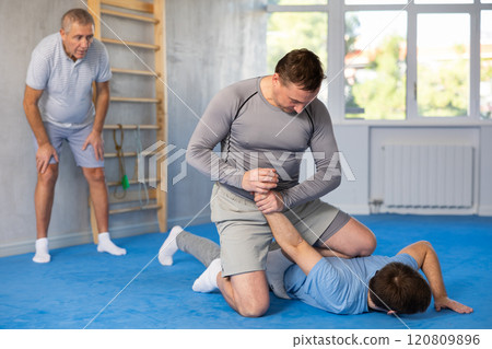 Man practicing painful armlock on male opponent at self defence training 120809896