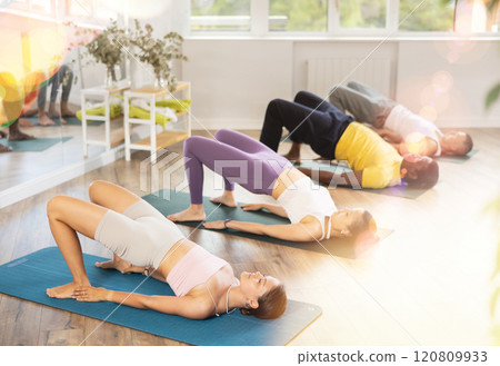 Young woman performing Setu Bandha Sarvangasana in yoga class 120809933