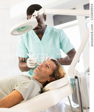 Man receiving facial cleansing with hydrogen and oxygen ions attachment Man receiving facial cleansing with hydrogen and oxygen ions attachment 120809934
