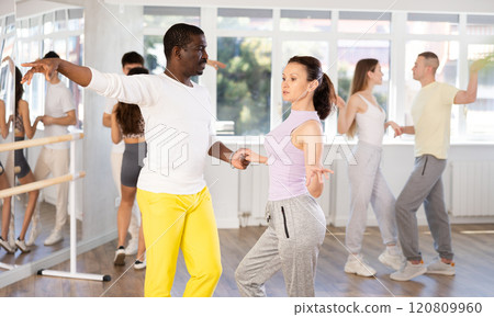 Middle-aged man and woman practicing samba dance in pair in training hall Middle-aged man and woman practicing samba dance in pair in training hall 120809960