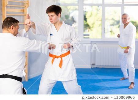 Concentrated guy honing punching techniques during kumite at karate training Concentrated guy honing punching techniques during kumite at karate training 120809966