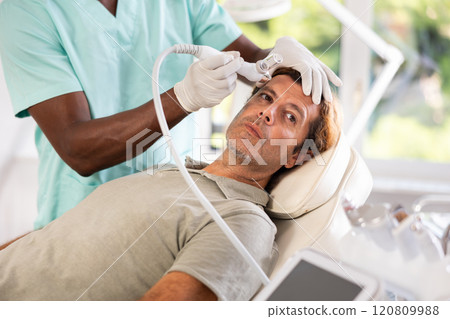 European man undergoes facial skin moisturizing procedure with hydrogen-oxygen hydrating nozzle European man undergoes facial skin moisturizing procedure with hydrogen-oxygen hydrating nozzle 120809988
