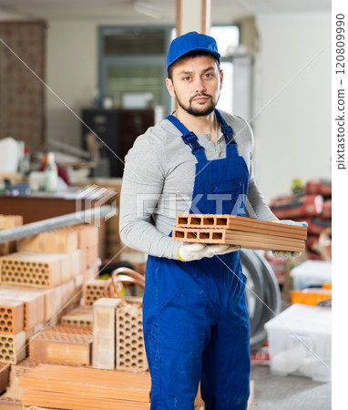 Young man stacking bricks at construction site Young man stacking bricks at construction site 120809990