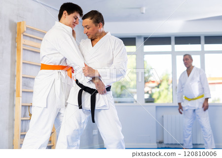 Jiu-jitsu master demonstrating basic grabs and throws in sparring with young fighter 120810006