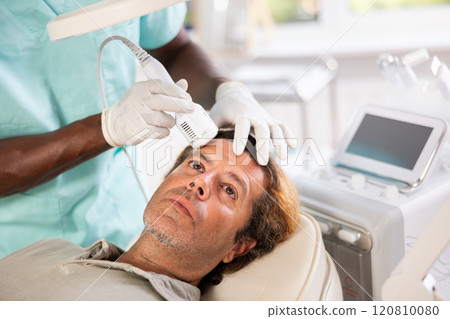 Adult man undergoing cosmetic facial treatment using cold hammer 120810080