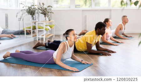 Asian woman performing Sphinx Pose during group yoga training Asian woman performing Sphinx Pose during group yoga training 120810225