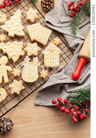Christmas cookies cooling on rack with festive decorations and rolling pin 120810493