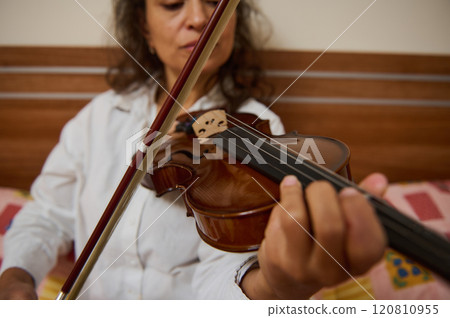 Close-up of woman playing a violin string instrument indoors 120810955