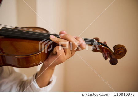 Close-up of a person playing a violin, showcasing skilled finger placement 120810973