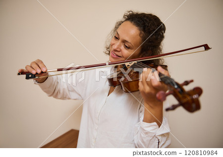 Woman joyfully playing the violin in a casual home setting 120810984