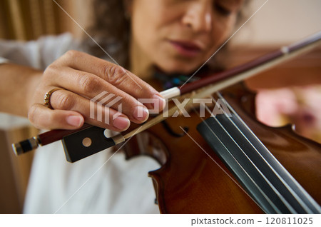 Close-up of woman playing violin with focused expression and gentle touch 120811025